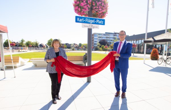 Karen Flügel und Bürgermeister Prof. Dr. Christoph Landscheidt enthüllen das neue Schild des Platzes, das den ehemaligen Bürgermeister Karl Flügel ehrt